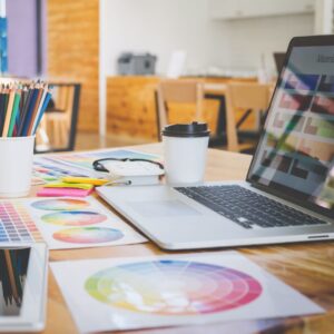 Image of a laptop with colour pallets, pencils and mood boards.